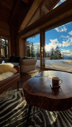 a living room filled with furniture and a large window covered in glass doors that look out onto the mountains