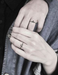 two people with rings on their fingers and one has an arrow tattoo on the ring