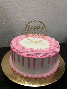 a birthday cake decorated with pink and white icing on a gold plated platter