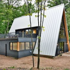 a house that is in the woods with a metal roof and two levels on it