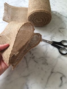 someone is holding some burlap on top of a pair of scissors