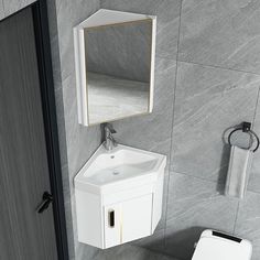 a bathroom with a toilet, sink and mirror next to a wall mounted towel dispenser