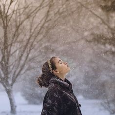 a woman standing in the snow with her eyes closed and looking up to the sky