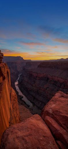 the sun is setting at the edge of a canyon with a river running through it