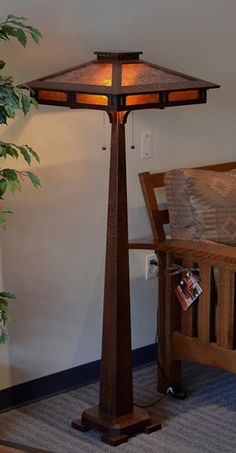 a lamp that is sitting on top of a table next to a bench and potted plant