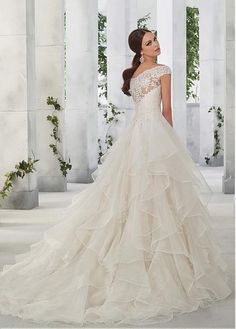 a woman in a wedding dress standing on a white floor with columns and greenery behind her