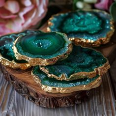 three pieces of green agate with gold foil on them sitting on a wooden table