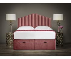 a bed with pink velvet headboard and two nightstands next to it on a wooden floor