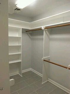 an empty walk in closet with white shelves