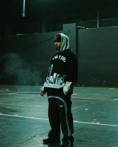 a man standing on top of a basketball court wearing a hoodie and sweatpants