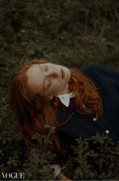 a woman with red hair is laying on the ground and has her eyes closed while wearing a blue dress