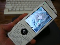 a person holding a cell phone in front of a keyboard