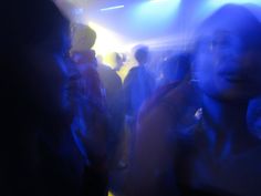 blurry image of people standing in a room with blue light coming from the ceiling