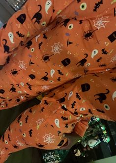 an orange halloween pajama set with black cats and ghostes on it's sleeves