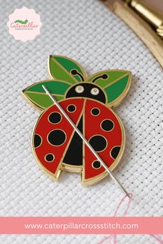 a ladybug pin sitting on top of a piece of fabric