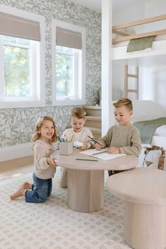 three children sitting at a table in a bedroom