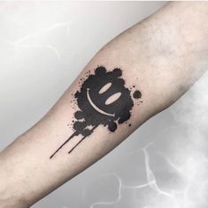 a black ink splattered arm with a smiley face on the left side of it