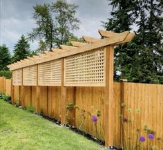 a wooden fence that has flowers growing on it and some grass in the foreground