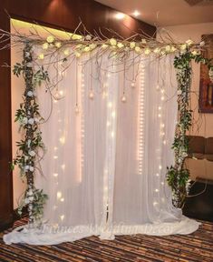 a room decorated with white flowers and greenery for a wedding or party, it is lit up by fairy lights