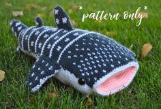 a knitted toy shark laying in the grass