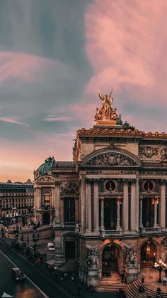 an old building with statues on top and stairs leading up to the entrance, in front of a cloudy sky