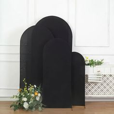 two black tombstones sitting on top of a wooden floor next to a vase with flowers