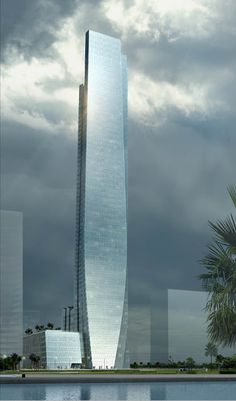 a very tall building sitting next to a body of water with palm trees in the foreground