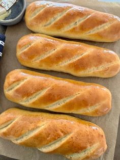 three loaves of bread sitting on top of a piece of wax paper next to a bowl