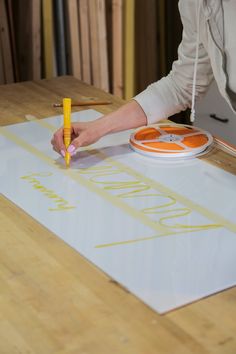 a woman is drawing on a large piece of paper with yellow marker and orange markers