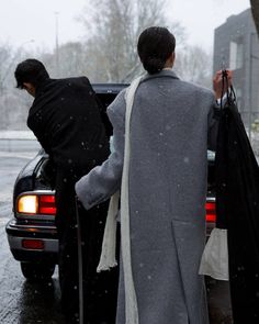 two people are getting out of a car in the snow