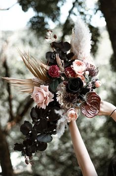 a person holding a bouquet with flowers and feathers