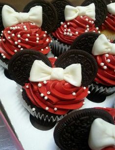 cupcakes with red and white frosting decorated like minnie mouse ears are on display