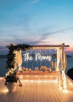 an outdoor wedding setup with lights and flowers on the deck at night, overlooking the ocean