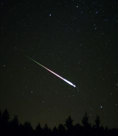 an object is seen in the night sky with stars and trees around it as well