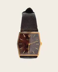 This vintage Rolex Cellini is a manual wind watch featuring a rare wood dial in 18K yellow gold from the 1970s. It boasts a precise timekeeping ability and is fully functional. The tonneau-shaped case contributes to its larger size compared to other Cellinis. It comes on a brown leather strap with a matching gold buckle, making it a stylish dress watch suitable for both men and women. The unique texture and color of the dial add to the charm of this timepiece. The watch also features gold stick hands and drilled lug holes. Both the case and case back are made of 18k yellow gold and are hallmarked on the back. All components, including the signed Rolex crown, case back, dial, and movement, are original. Rolex Crown, Rolex Cellini, Vintage Rolex, Brown Leather Strap, Dress Watch, Gold Wood, Fine Jewelry Collection, Vintage Watches, The Watch