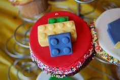 cupcakes decorated with lego blocks and sprinkles on a metal stand