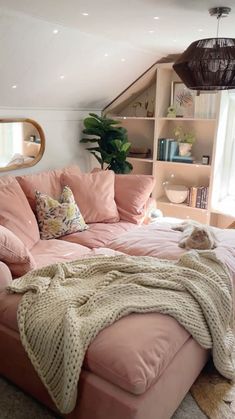 a pink couch with a blanket on it in front of a mirror and bookshelf