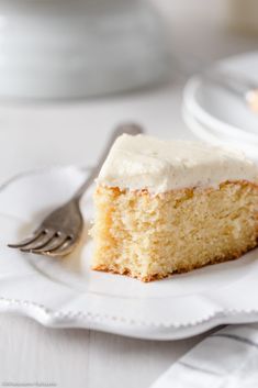 a piece of cake on a white plate with a fork next to it and another slice in the background