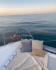 the back end of a boat with pillows on it's deck and water in the background