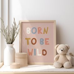 a teddy bear sitting on a shelf next to a framed print with the words born to be wild