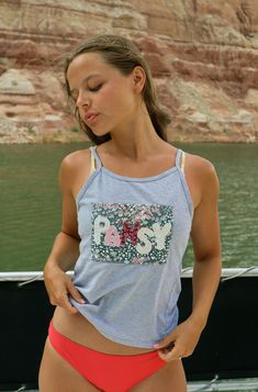 a woman standing in front of a body of water with her hands on her hips