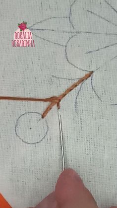 someone is stitching something on the fabric with a pair of scissors and thread in front of them