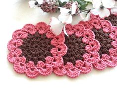 two crocheted doily with flowers on the table