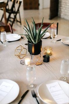 the table is set with white plates, silverware and an aloema plant