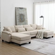 a living room with a large sectional couch and white rugs on the hardwood floor