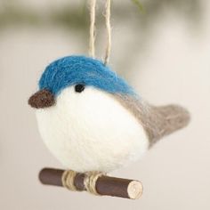 a blue and white bird ornament hanging from a branch with a twig