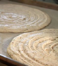 two uncooked pizza doughs sitting on top of a pan