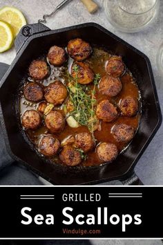 some meatballs are cooking in a skillet on the table with lemon wedges