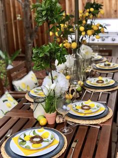 the table is set with lemons and flowers in vases, plates and utensils