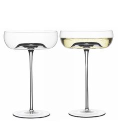 two wine goblets filled with white wine on top of each other, side by side